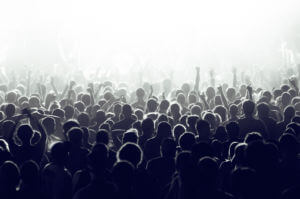 Crowd cheering and watching a band on stage, blinded by stage lights.